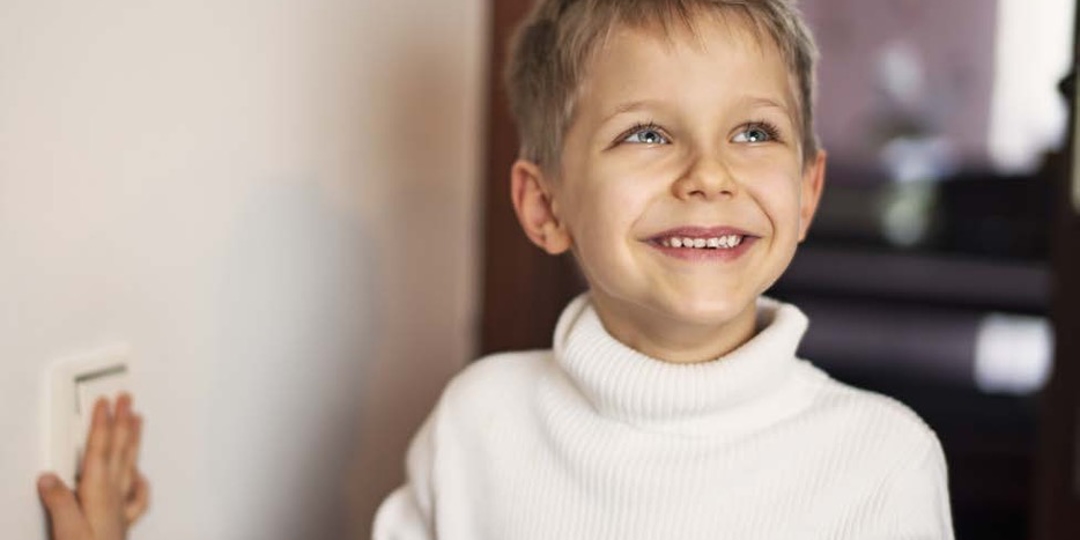 Little kid smiling while hold light switch
